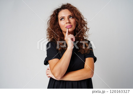 Thoughtful woman pondering ideas against a neutral background Thoughtful woman pondering ideas against a neutral background 120163327