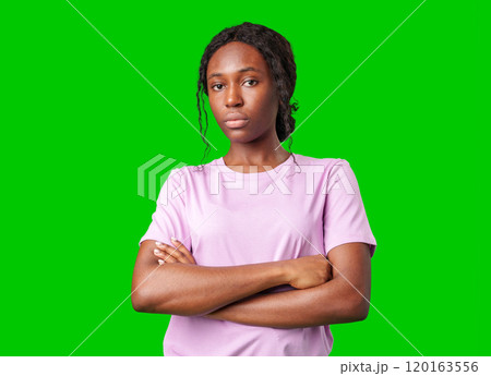 Young woman with an expression of contemplation poses against a bright green background 120163556