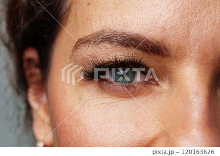 Close-up view of a woman's striking blue eyes with long lashes 120163626