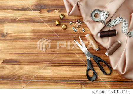 Crafting tools and materials arranged on a wooden table for sewing projects Crafting tools and materials arranged on a wooden table for sewing projects 120163710