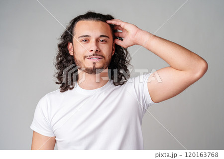 Young man with curly hair poses confidently against a plain background Young man with curly hair poses confidently against a plain background 120163768