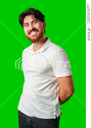 A smiling young man with a beard poses against a bright green background A smiling young man with a beard poses against a bright green background 120163977