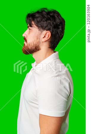 Profile view of a man with a beard wearing a white polo shirt against a bright green background Profile view of a man with a beard wearing a white polo shirt against a bright green background 120163984