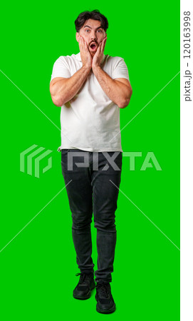 Young man expresses surprise in front of a bright green background 120163998