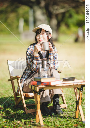 キャンプで飲み物を飲む若い女性 120164906