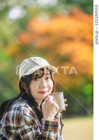キャンプで飲み物を飲む若い女性 120164910