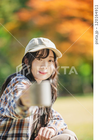 キャンプで飲み物を飲む若い女性 120164911