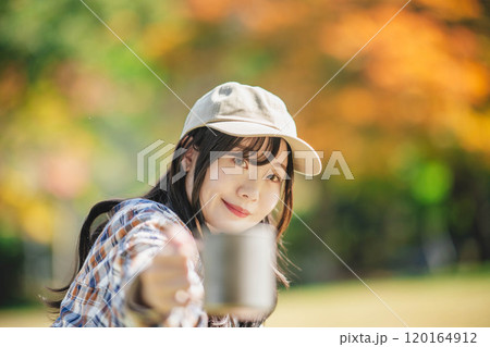 キャンプで飲み物を飲む若い女性 120164912