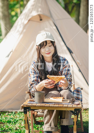 キャンプ場で食事をとる女性 120165373