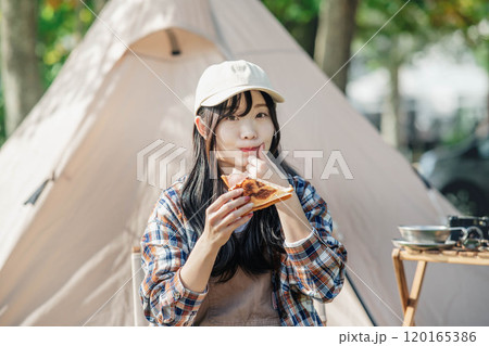 キャンプ場で食事をとる女性 120165386