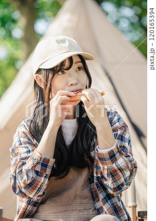 キャンプ場で食事をとる女性 120165394