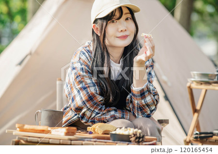 キャンプ場でお菓子を食べる女性 120165454