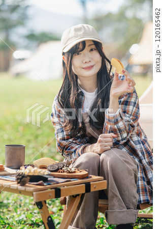 キャンプ場でお菓子を食べる女性 キャンプ場でお菓子を食べる女性 120165462