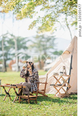 キャンプ場でお菓子を食べる女性 120165477