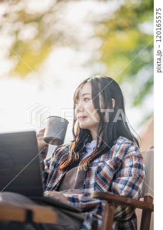 キャンプ場で仕事をする若い女性 120165575