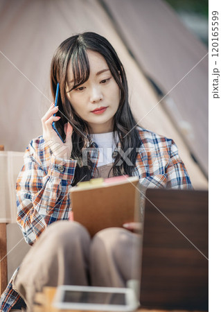 キャンプ場で仕事をする若い女性 120165599