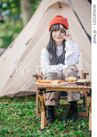 キャンプ場でお菓子を食べる女性 120165639