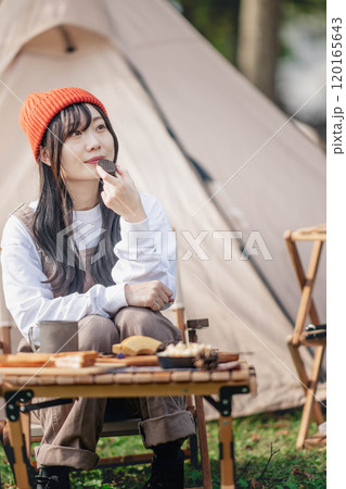 キャンプ場でお菓子を食べる女性 120165643