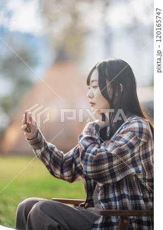 キャンプ場でアウトドアチェアに座る女性 キャンプ場でアウトドアチェアに座る女性 120165747