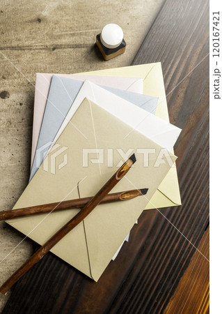 Two calligraphy reeds covered ink with inkwell and stack of envelopes on the table Two calligraphy reeds covered ink with inkwell and stack of envelopes on the table 120167421