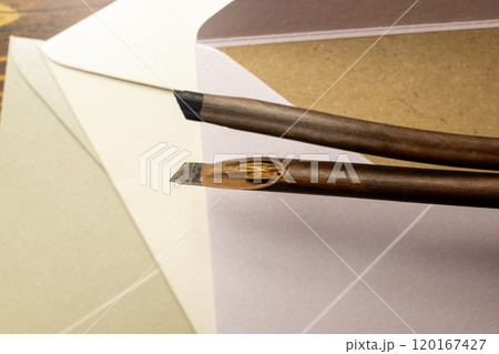 Two calligraphy reeds covered ink with stack of envelopes and brown card on the table Two calligraphy reeds covered ink with stack of envelopes and brown card on the table 120167427