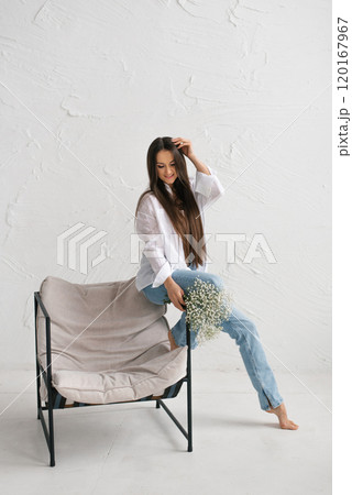 Happy woman sits in a chair with a bouquet of flowers in her lap Happy woman sits in a chair with a bouquet of flowers in her lap 120167967