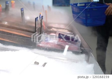 A fillet of fresh fish rests on an icy counter in the store under a cooling spray 120168159