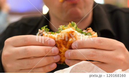 Man eating veggie burger in a vegan cafe or restaurant. Man eating veggie burger in a vegan cafe or restaurant. 120168160