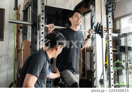ジム・パーソナルジムのマンツーマン指導で追い込む・効かせるアジア人男性とトレーナーの男性 120168633