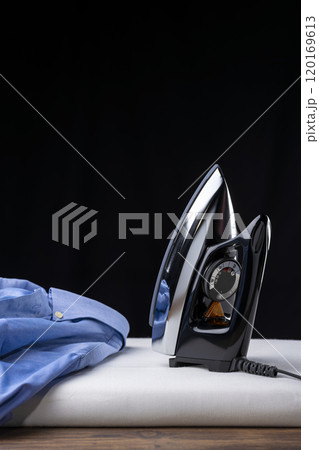 黒背景にアイロン台の上に置かれたアイロンとワイシャツ 黒背景にアイロン台の上に置かれたアイロンとワイシャツ 120169613