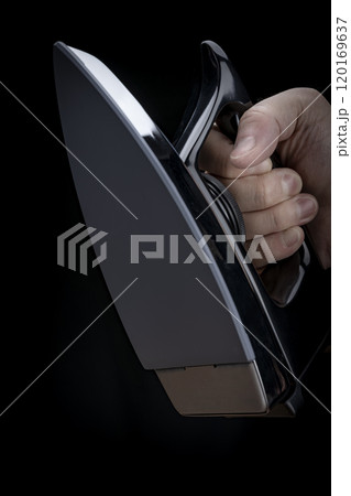 黒背景にアイロンを手に持つ男性の手のクローズアップ 120169637