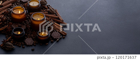 Soy scented candle in a jar. Coffee beans, anise, cinnamon spices. The candles are burning. Dark copy space background. Soy scented candle in a jar. Coffee beans, anise, cinnamon spices. The candles are burning. Dark copy space background. 120171637