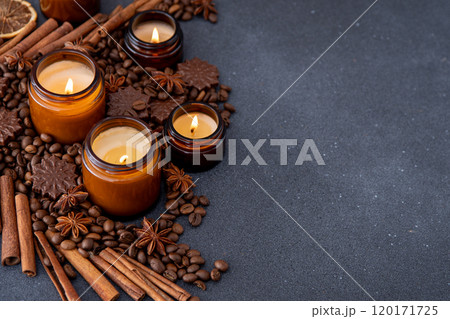 Soy scented candle in a jar. Coffee beans, anise, cinnamon spices. The candles are burning. Dark copy space background. 120171725