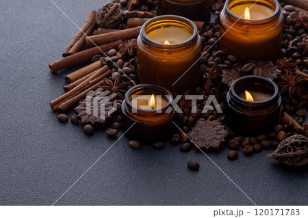 Soy scented candle in a jar. Coffee beans, anise, cinnamon spices. The candles are burning. Dark background. Soy scented candle in a jar. Coffee beans, anise, cinnamon spices. The candles are burning. Dark background. 120171783