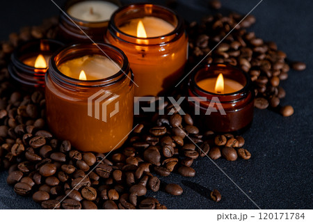 Soy scented candle in a jar. Coffee beans, anise, cinnamon spices. The candles are burning. Dark background. Soy scented candle in a jar. Coffee beans, anise, cinnamon spices. The candles are burning. Dark background. 120171784