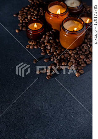 Soy scented candle in a jar. Coffee beans, anise, cinnamon spices. The candles are burning. Dark copy space background. Soy scented candle in a jar. Coffee beans, anise, cinnamon spices. The candles are burning. Dark copy space background. 120171785