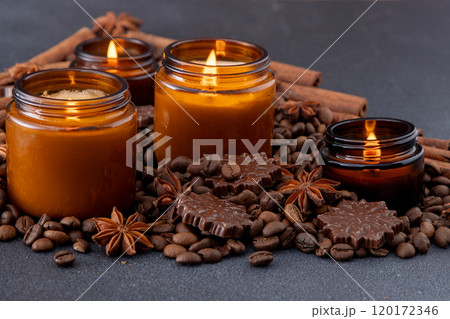 Soy scented candle in a jar. Coffee beans, anise, cinnamon spices. The candles are burning. Dark background. Soy scented candle in a jar. Coffee beans, anise, cinnamon spices. The candles are burning. Dark background. 120172346