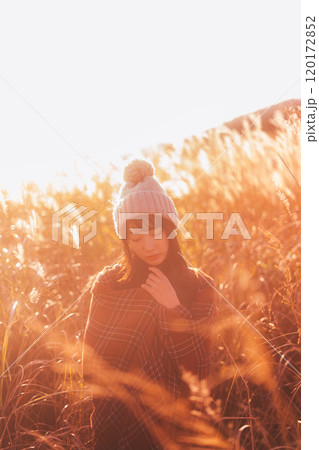 夕日に染まるススキに囲まれる女性 夕日に染まるススキに囲まれる女性 120172852