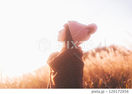 夕日に染まるススキに囲まれる女性 夕日に染まるススキに囲まれる女性 120172856