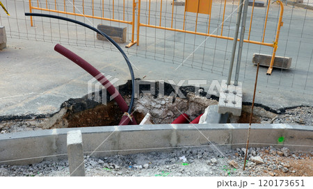 Street construction site revealing underground communications infrastructure in a city setting 120173651