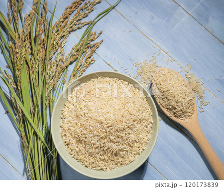 Brown rice in wooden bowl with spoon and ears gray Brown rice in wooden bowl with spoon and ears gray 120173839