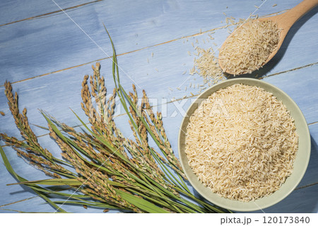 Brown rice in wooden bowl with ears of rice and spoonful 120173840