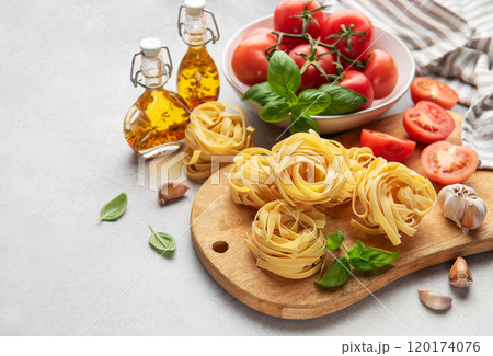 Italian tagliatelle pasta nests with tomatoes, basil and olive oil ready for cooking 120174076