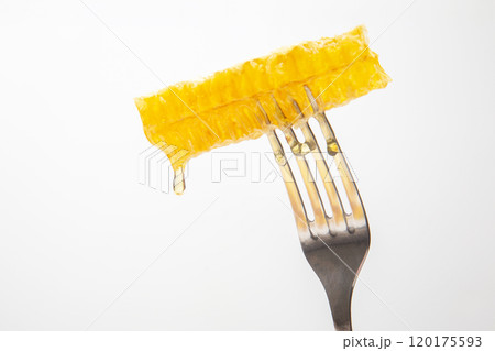 Drops of fresh honey drip from wax honey on a table fork. vitamin nutrition and bee product. 120175593