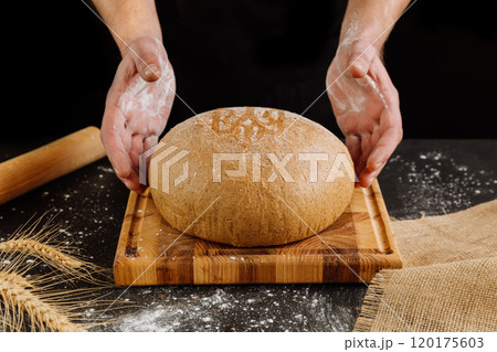 Freshly baked artisan bread on a wooden board with flour-dusted hands for rustic bakery vibes Freshly baked artisan bread on a wooden board with flour-dusted hands for rustic bakery vibes 120175603