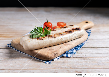 Grilled bratwurst sausages with tomatoes on wooden table 120175854