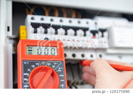 Electrician Measuring Voltage with Multimeter in Circuit Breaker Panel 120175890