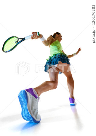 Rear view of athlete, with her racket swung back, embodies focus and precision, ready to unleash powerful strike against white studio background. Rear view of athlete, with her racket swung back, embodies focus and precision, ready to unleash powerful strike against white studio background. 120176283