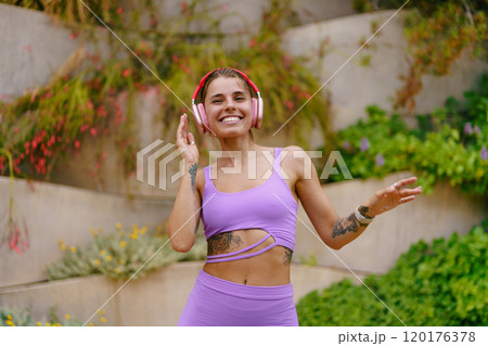 An Energetic and Joyful Woman Enjoying Listening to Music While Dressed in Activewear Attire 120176378