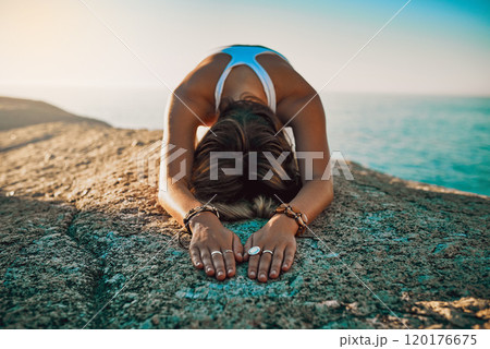 Feel the positivity flowing through your body. Shot of a woman practising the child pose at then beach. 120176675